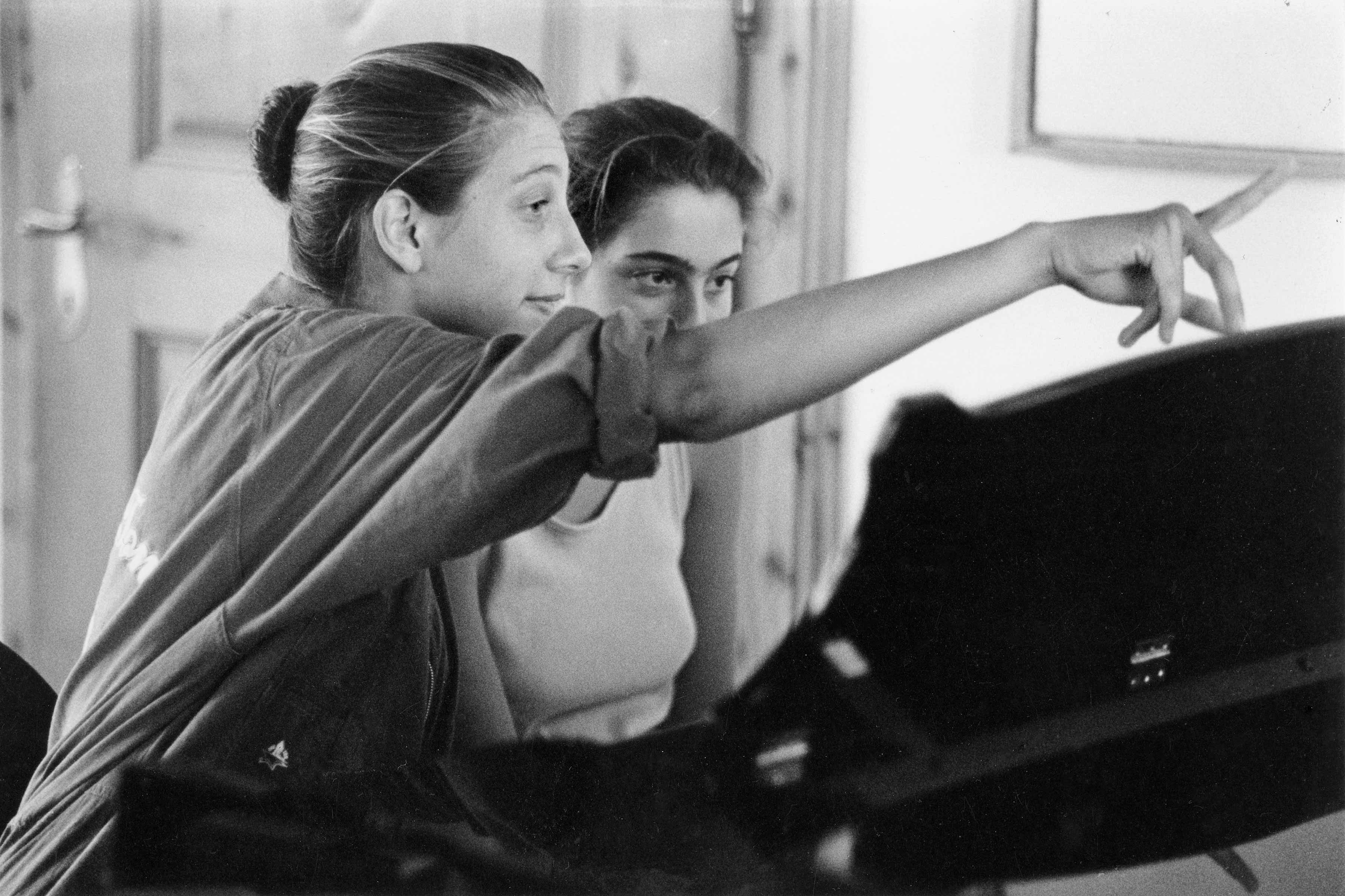 Eva 15 years old playing piano with her sister and point the notes